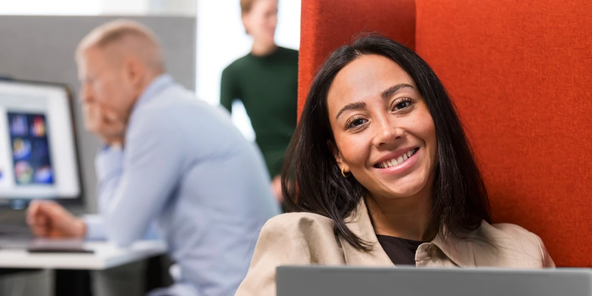 En kvinna sitter i en fåtölj med en bärbar dator på ett kontor.